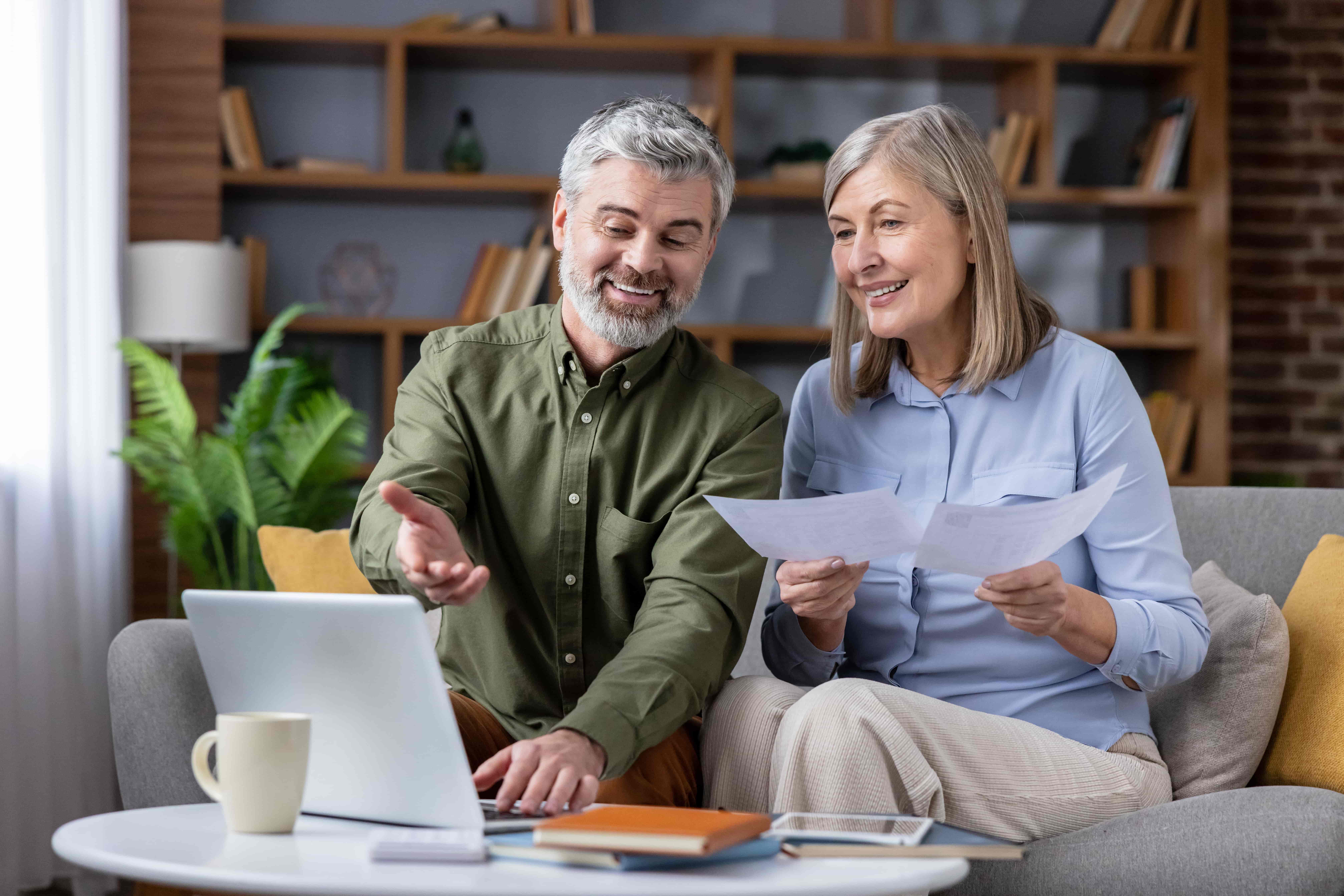 Senior couple sitting on a sofa discussing financial documents